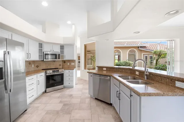 a kitchen with stainless steel appliances granite countertop a sink and a refrigerator