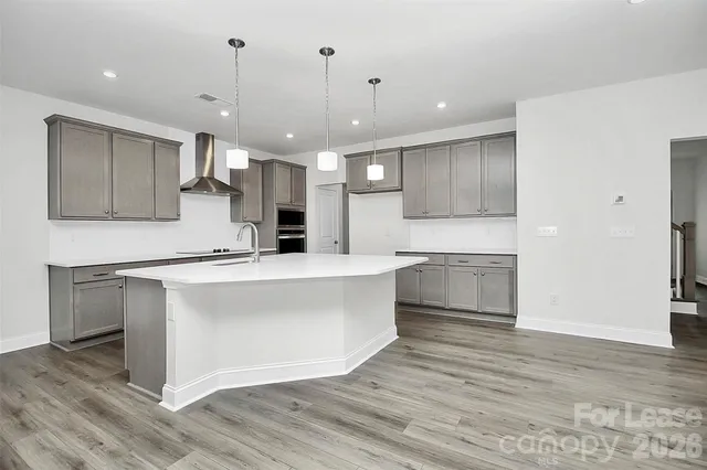 a large kitchen with kitchen island a stove a sink dishwasher a refrigerator and white cabinets with wooden floor