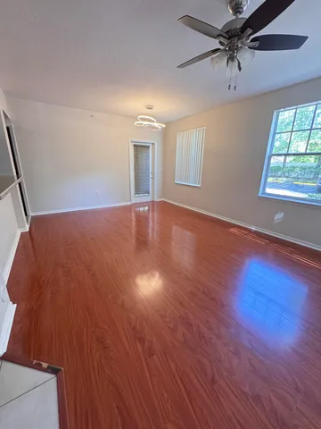 a view of an empty room with a window and wooden floor