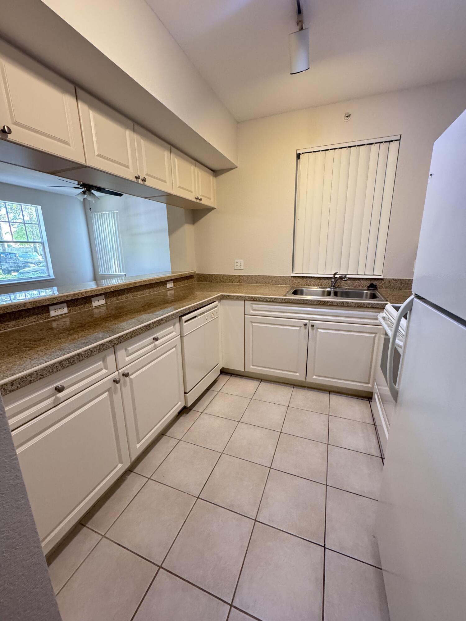 6906 West Sample Road, Unit 6906 Pompano Beach, FL 33063 - Photo 4 of 10 a kitchen with cabinets and a stove top oven
