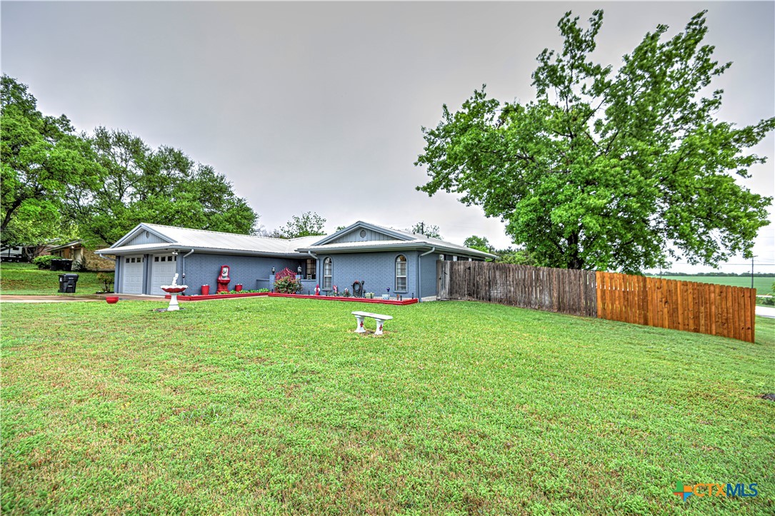 a view of a tiny house with a yard and large trees