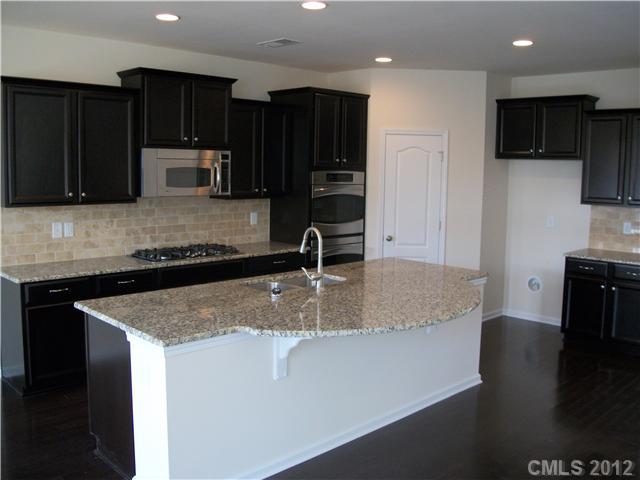 1240 Screech Owl Road Waxhaw, NC 28173 - Photo 4 of 14 a kitchen with kitchen island granite countertop a sink a stove and refrigerator