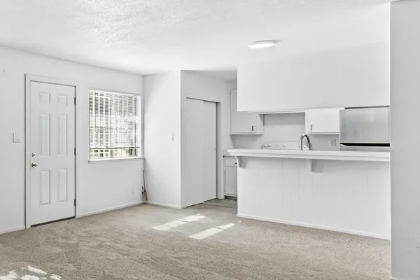 a view of kitchen with refrigerator and white cabinets