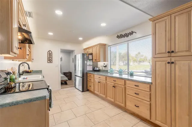 a large kitchen with granite countertop a large counter top space a sink stainless steel appliances and cabinets