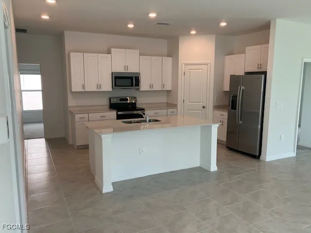 a kitchen with stainless steel appliances granite countertop a refrigerator a stove and a sink