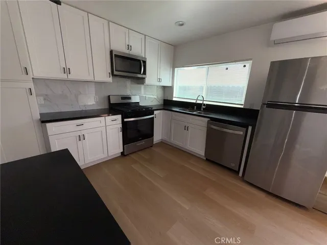 a kitchen with granite countertop a refrigerator sink and white cabinets