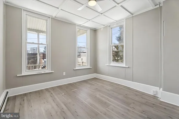 an empty room with wooden floor and windows