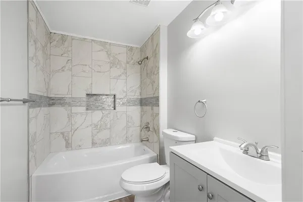 a bathroom with a bathtub shower sink vanity and toilet