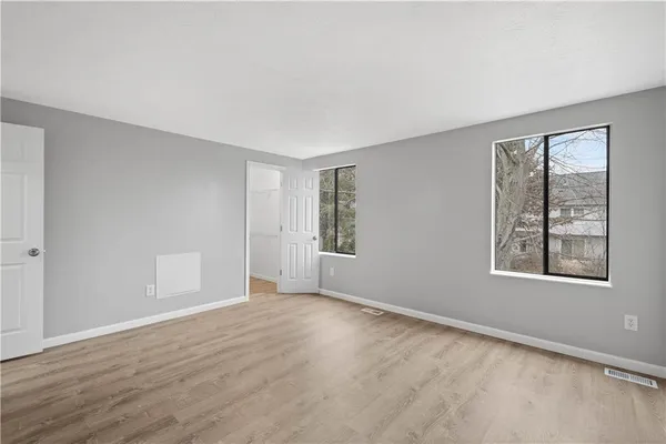 a view of an empty room with wooden floor and a window