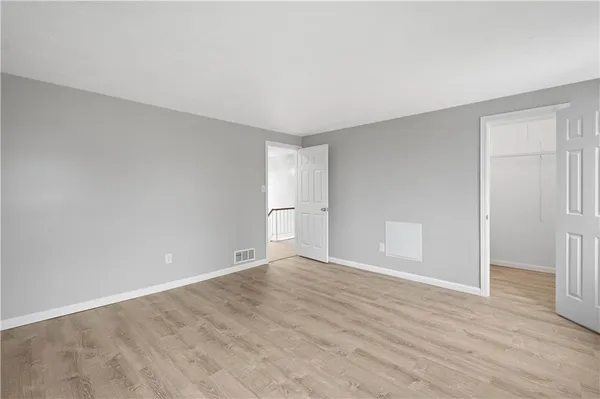 a view of an empty room with wooden floor and window