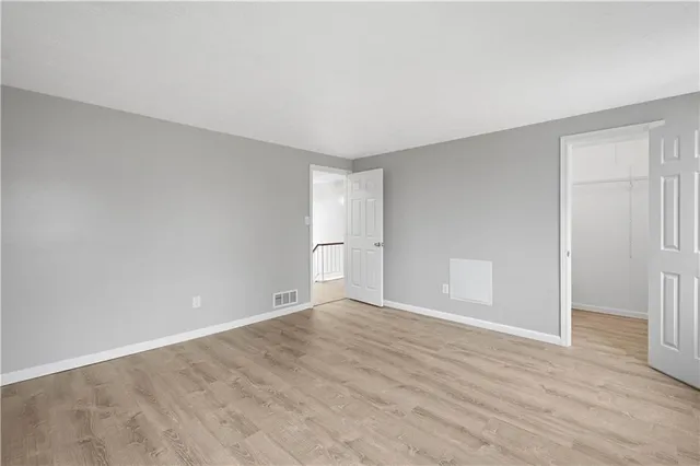 a view of an empty room with wooden floor and window