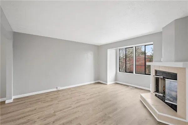 a view of an empty room with a window and fireplace