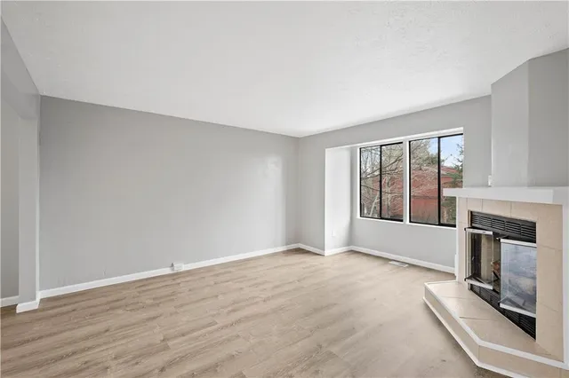 a view of an empty room with a window and fireplace