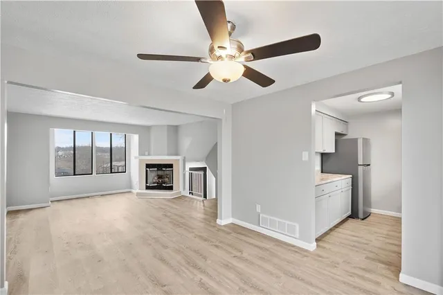 a view of a livingroom with a fireplace a ceiling fan and windows