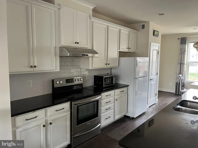 a kitchen with granite countertop white cabinets and black appliances