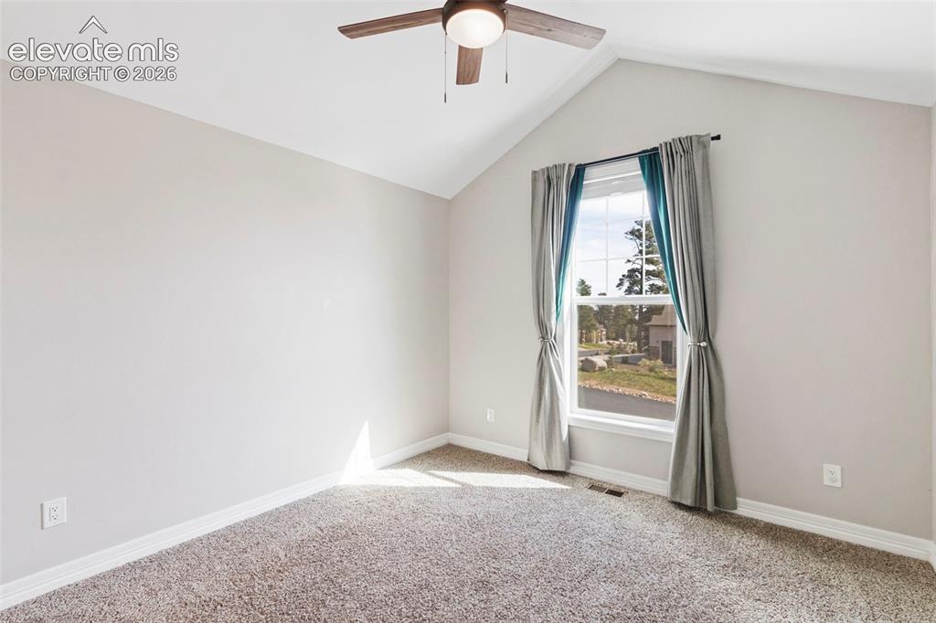 5375 Old Star Ranch View Colorado Springs, CO 80906 - Photo 21 of 47 Room featuring a vaulted ceiling with a ceiling fan, a window with exterior views, light-toned carpeting, and white baseboards