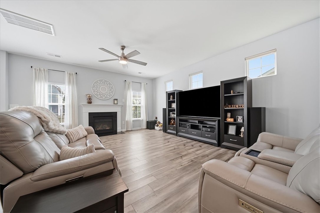 208 Grassy Creek Way Pendleton, SC 29670 - Photo 18 of 43 A comforting living area with a cozy fireplace and durable hardwood-style flooring awaits.