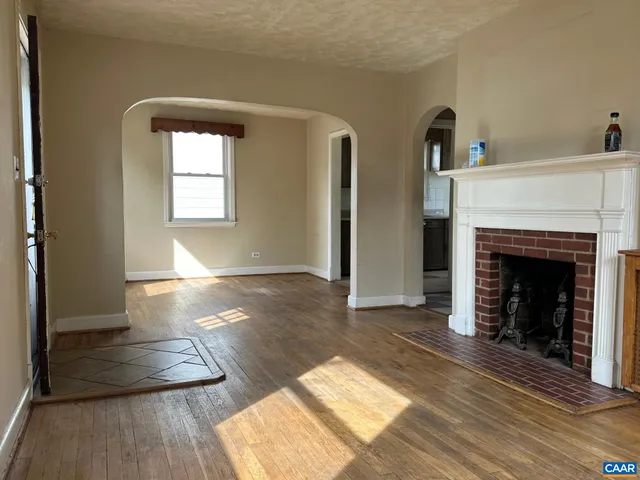 a view of a livingroom with wooden floor and a fireplace