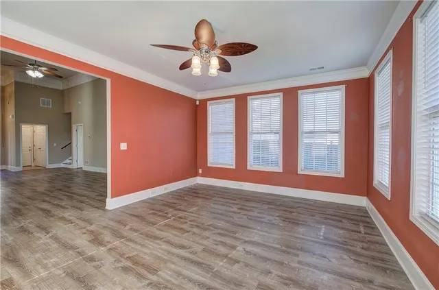 a view of an empty room with a window and wooden floor