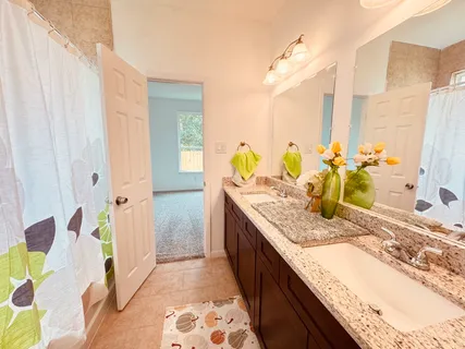 a bathroom with a granite countertop sink a mirror and shower