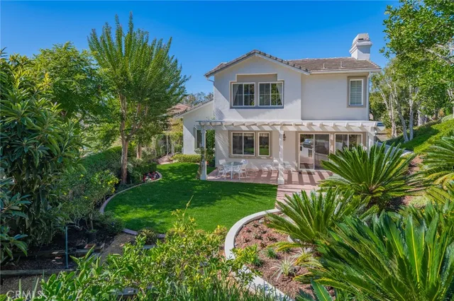a view of a swimming pool with lounge chair and large trees