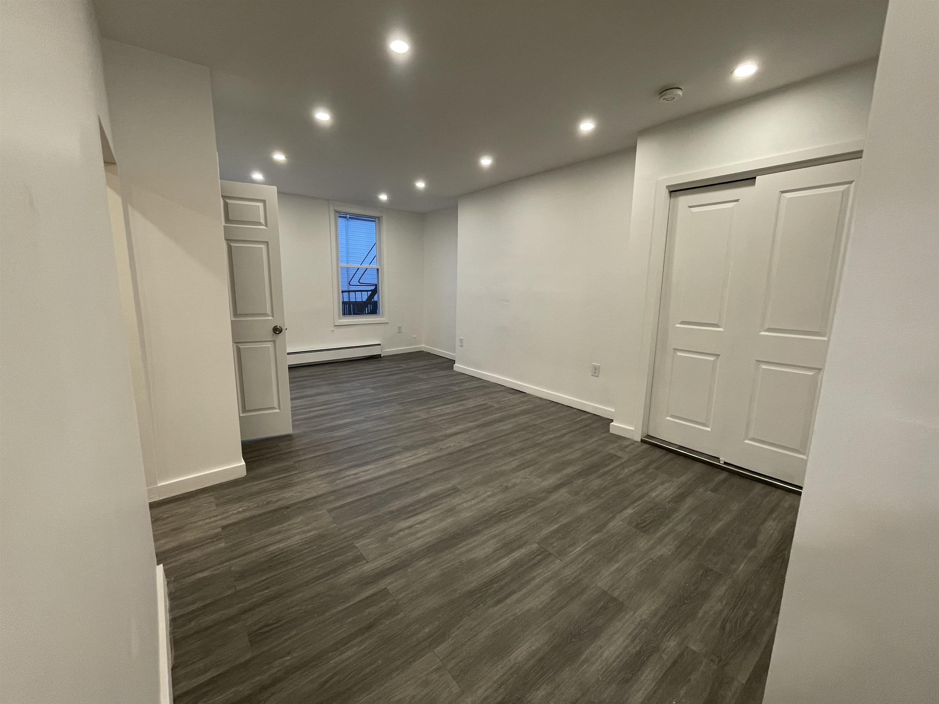 516 Paterson Plank Road, Unit 2R Jersey City, NJ 07307 - Photo 10 of 13 an empty room with wooden floor and windows
