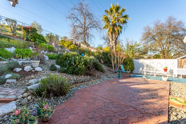 a view of a street with flower plants and wooden fence