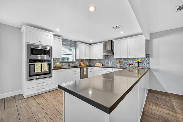 a large kitchen with granite countertop lots of counter space a sink and appliances