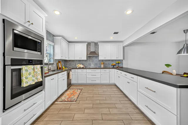 a large kitchen with stainless steel appliances granite countertop a stove a sink and a microwave