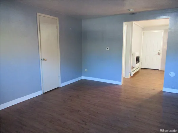 an empty room with wooden floor & windows
