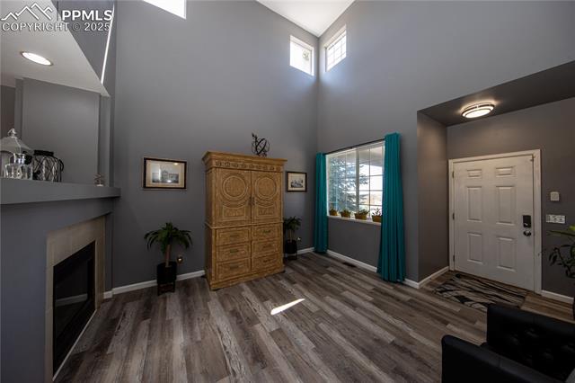 7511 Coffee Road Peyton, CO 80831 - Photo 8 of 38 Entrance foyer with a towering ceiling, wood finished floors, baseboards, and a fireplace