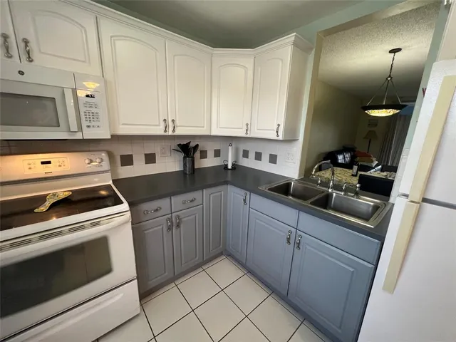 a kitchen with granite countertop white cabinets and white appliances