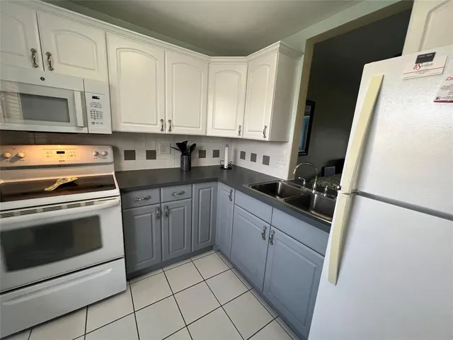 a kitchen with granite countertop white cabinets and white appliances