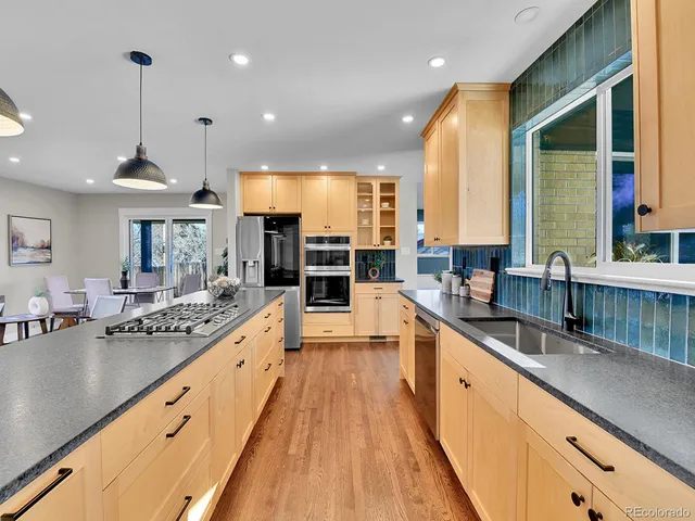 a large kitchen with kitchen island a large window a sink and stainless steel appliances