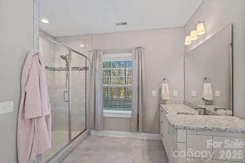 a bathroom with a granite countertop sink a mirror and shower