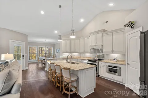 a kitchen with a stove a sink a microwave a dining table and chairs