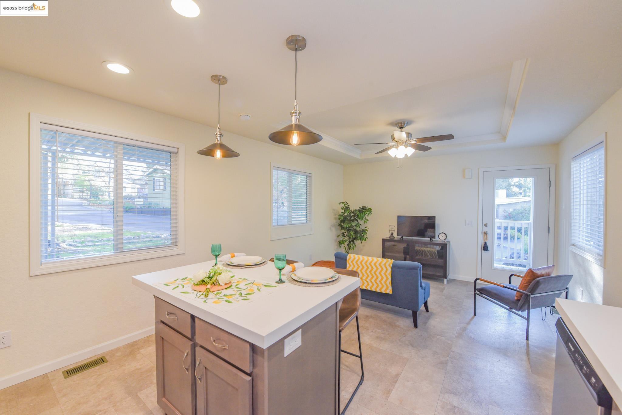 10956 Green Street Columbia, CA 95310 - Photo 24 of 45 Kitchen featuring hanging light fixtures, light countertops, a tray ceiling, a kitchen breakfast bar, and a ceiling fan