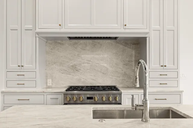 a kitchen with granite countertop white cabinets and a stove