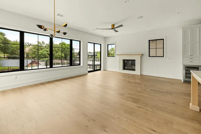 an empty room with fireplace fan and windows