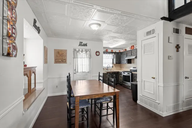 a kitchen with stainless steel appliances granite countertop a stove a refrigerator a dining table and chairs with wooden floor