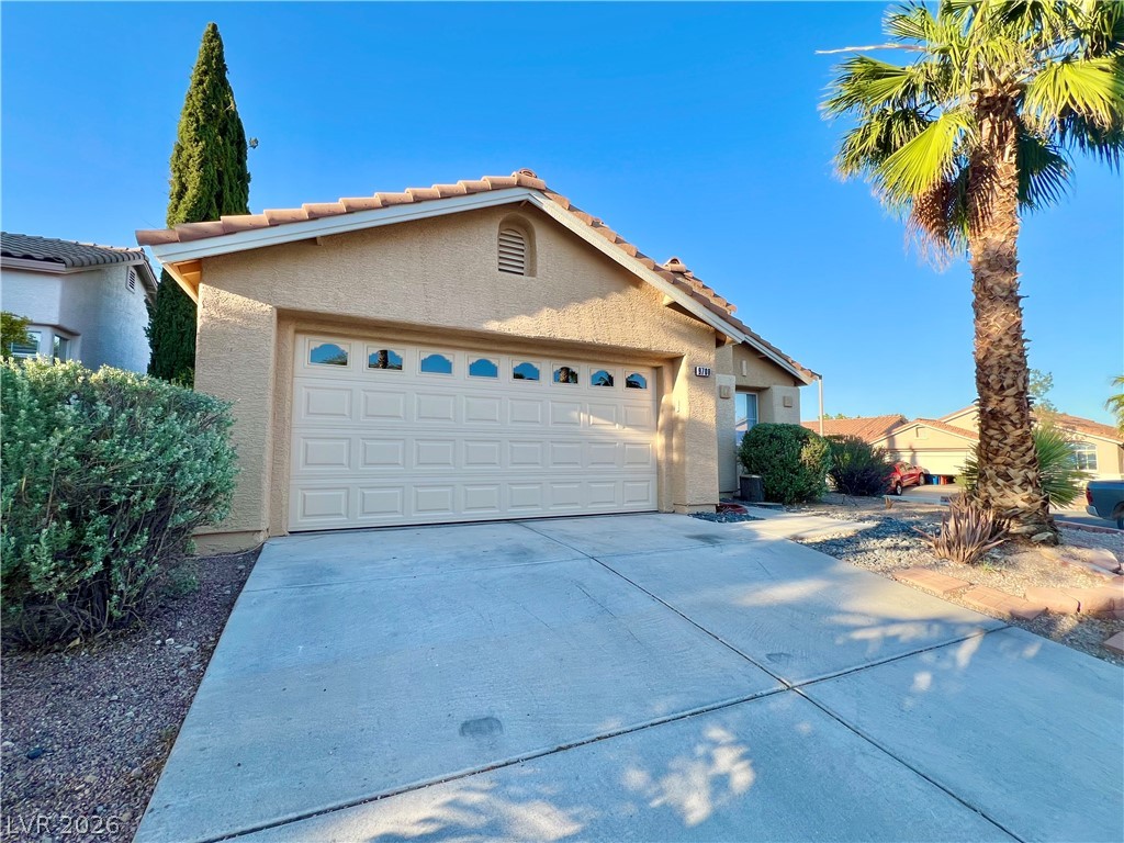 9708 Ridge Creek Place Las Vegas, NV 89134 - Photo 33 of 34 Nice afternoon shade. A classic facade with a tan exterior and an attached garage, nestled among desert landscaping.