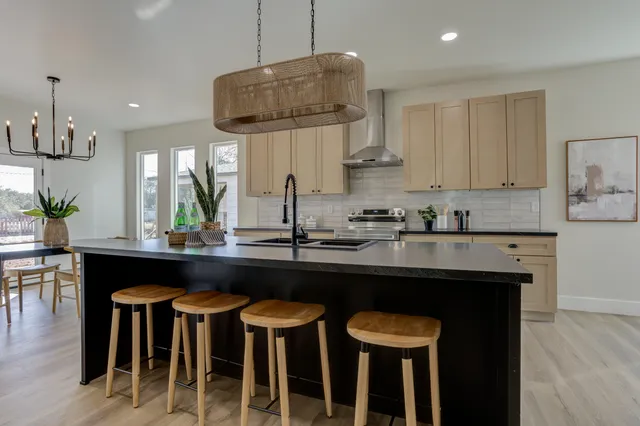 a kitchen with stainless steel appliances granite countertop a dining table chairs and white cabinets