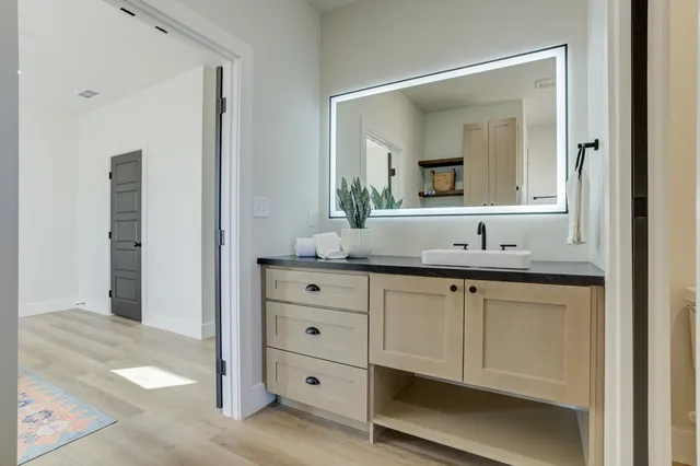 a bathroom with a granite countertop sink a mirror and shower