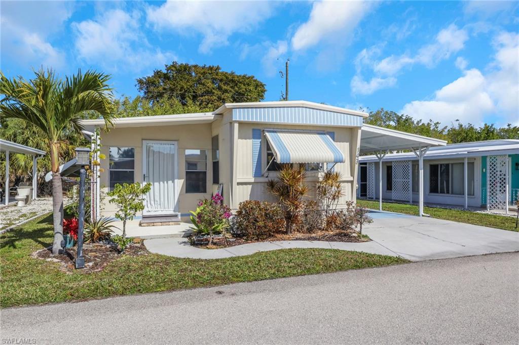 View of front of property featuring an attached carport, concrete driveway, and a front yard