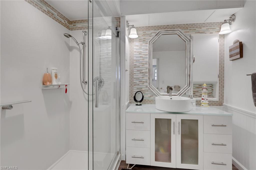 143 Moorhead Manor, Unit 143 Naples, FL 34112 - Photo 14 of 35 Full bath with vanity, a shower stall, wainscoting, and tasteful backsplash
