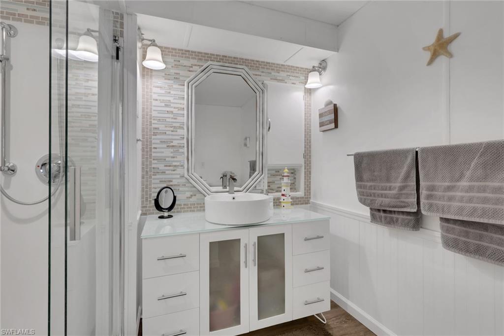 143 Moorhead Manor, Unit 143 Naples, FL 34112 - Photo 15 of 35 Full bathroom featuring vanity, wainscoting, a stall shower, and dark wood-type flooring