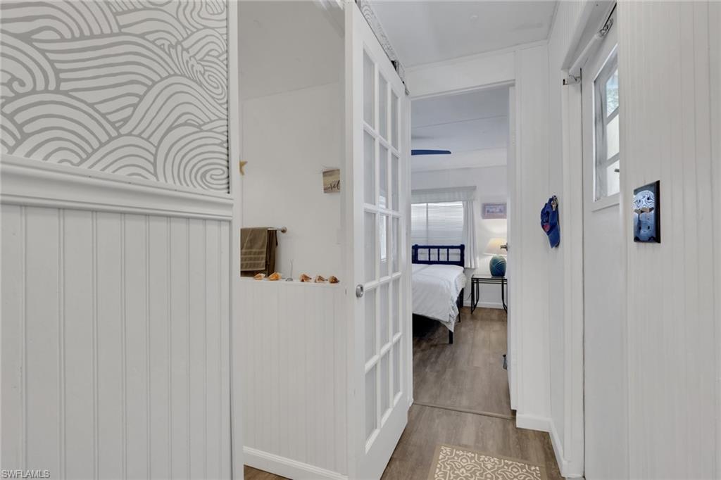 143 Moorhead Manor, Unit 143 Naples, FL 34112 - Photo 21 of 35 Corridor featuring wood finished floors and healthy amount of natural light