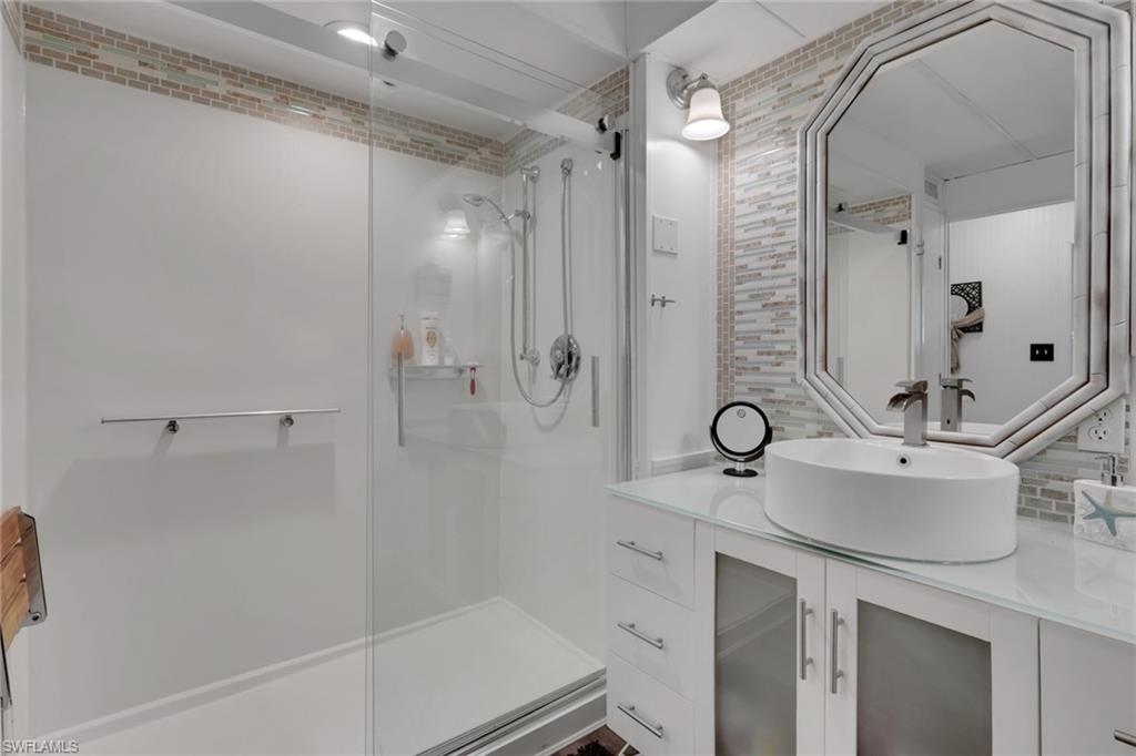143 Moorhead Manor, Unit 143 Naples, FL 34112 - Photo 32 of 35 Bathroom with vanity, tasteful backsplash, and a stall shower