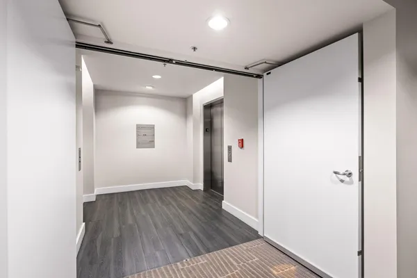 a view of a hallway with wooden floor and a bathroom