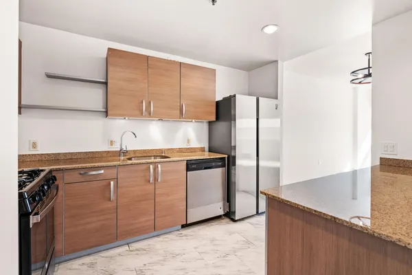 a kitchen with stainless steel appliances granite countertop a refrigerator a sink and a stove